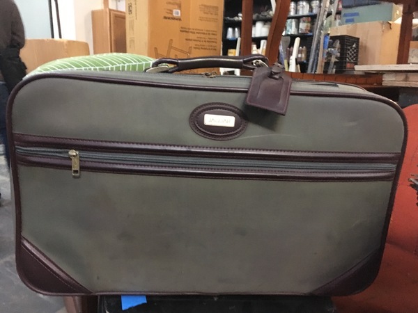 Green and brown leather suitcase with tag